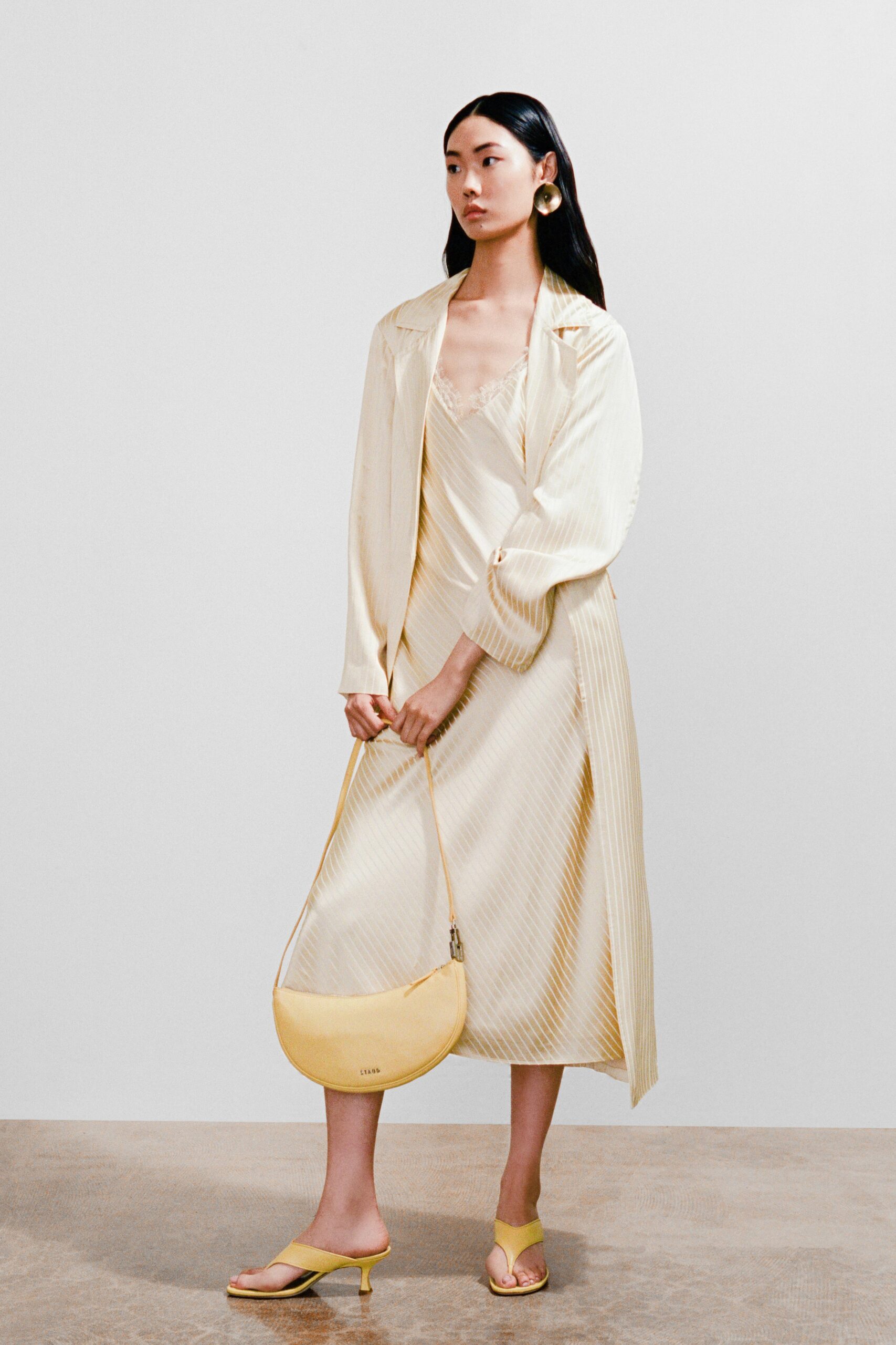 A relaxed cream silk dress layered with a long-sleeve coat featuring a V-neckline and striped design.