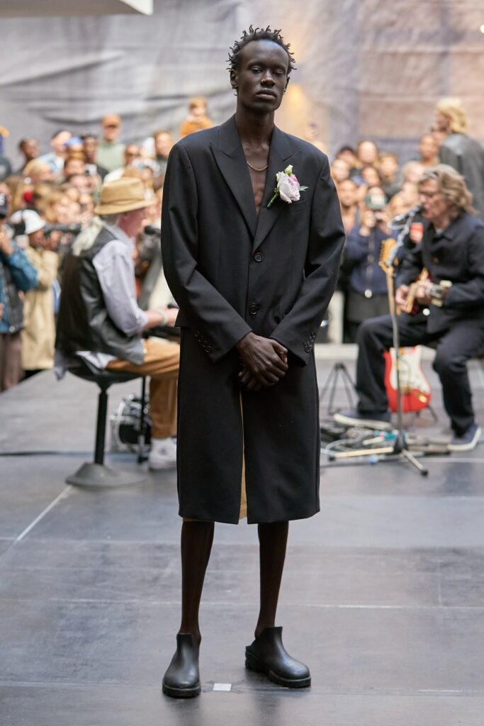An oversized black wool coat with long sleeves and a collared design, featuring button details.