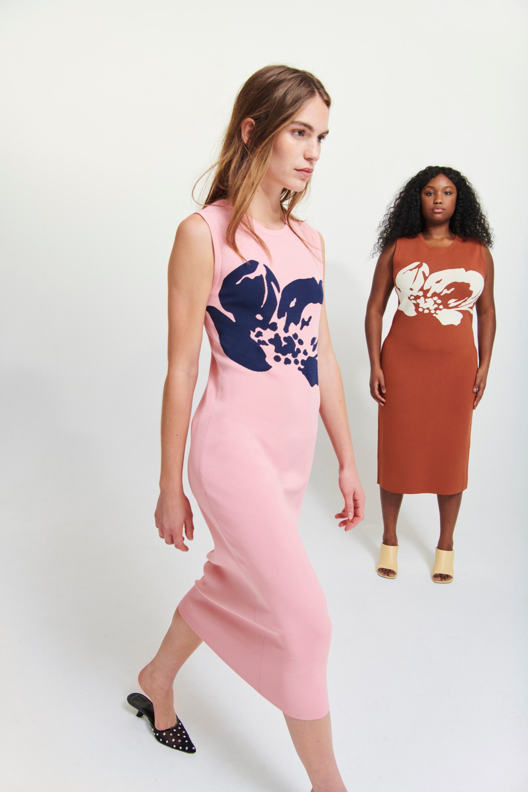 A fitted pink sleeveless dress with a high-neck and printed floral design.