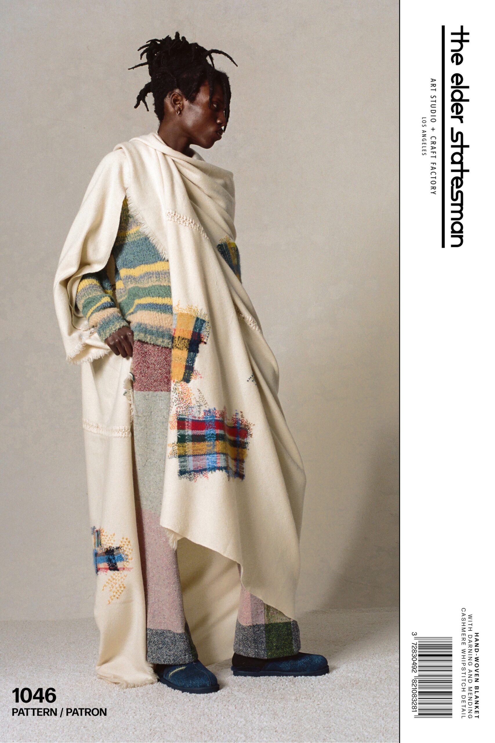 A relaxed-fit beige wool cape paired with multicolor pants featuring a layered design.