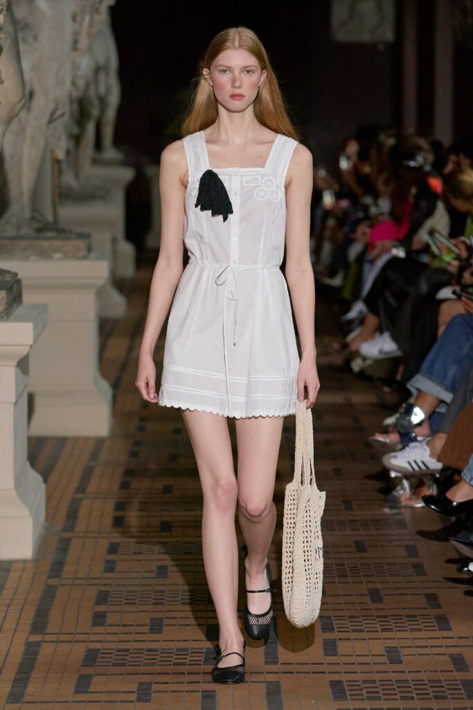 A fitted white cotton sleeveless dress with a V-neckline and tiered design details.