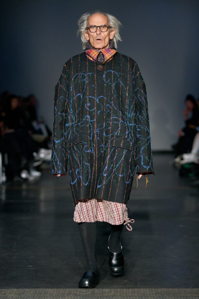 An oversized black coat dress with long sleeves and a layered design.