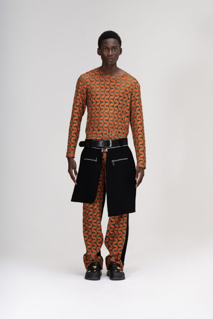 A relaxed fit long-sleeve printed orange top paired with black pants.