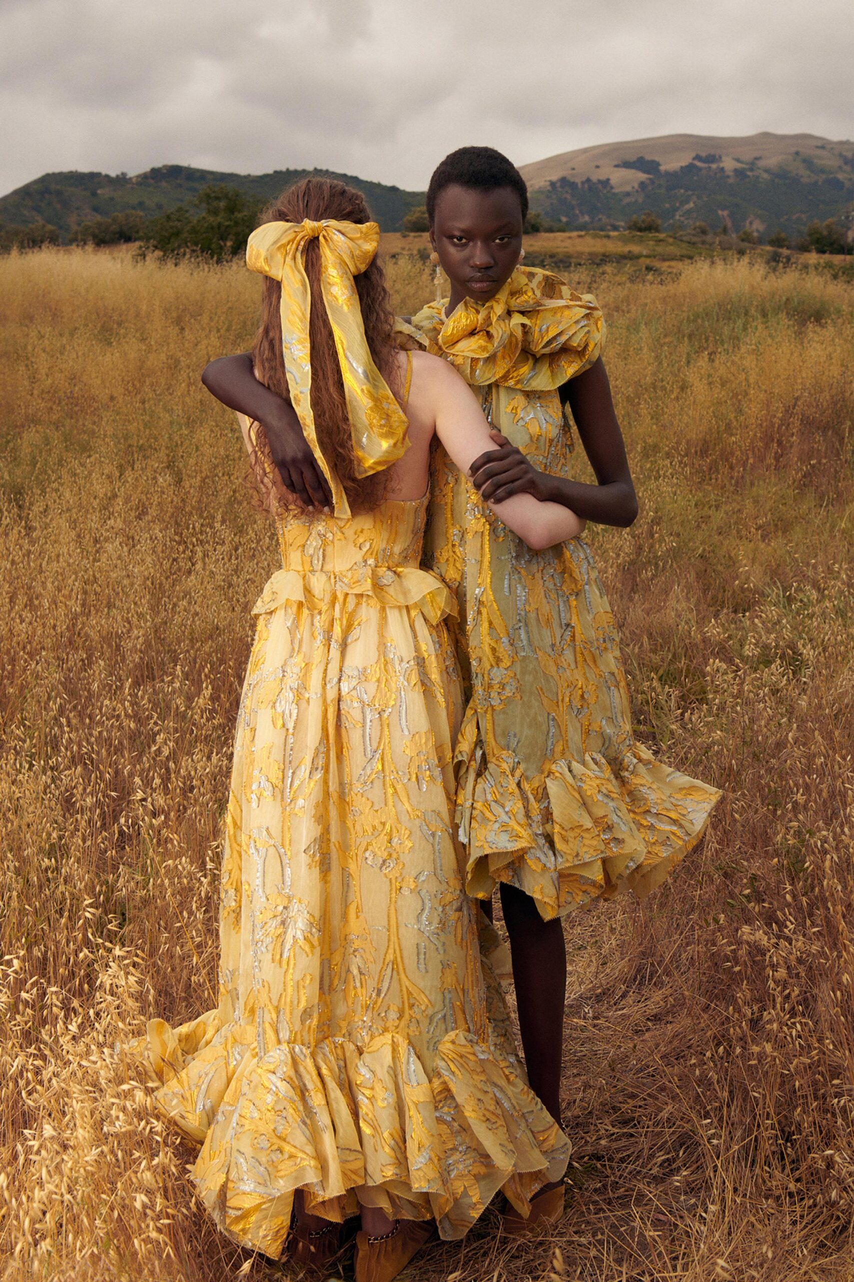 A fitted yellow silk dress with a V-neckline and tiered design details.