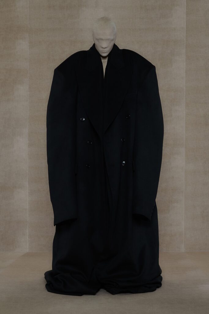 An oversized black wool coat with long sleeves and an asymmetric design.