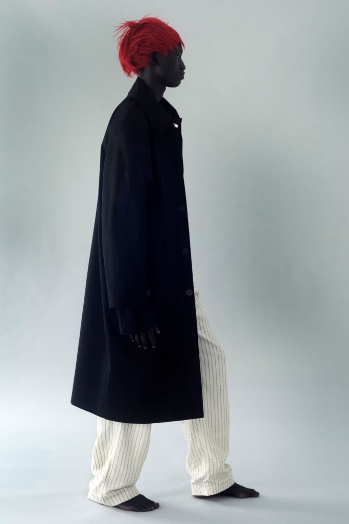 A relaxed black coat paired with white striped pants featuring a collared design.