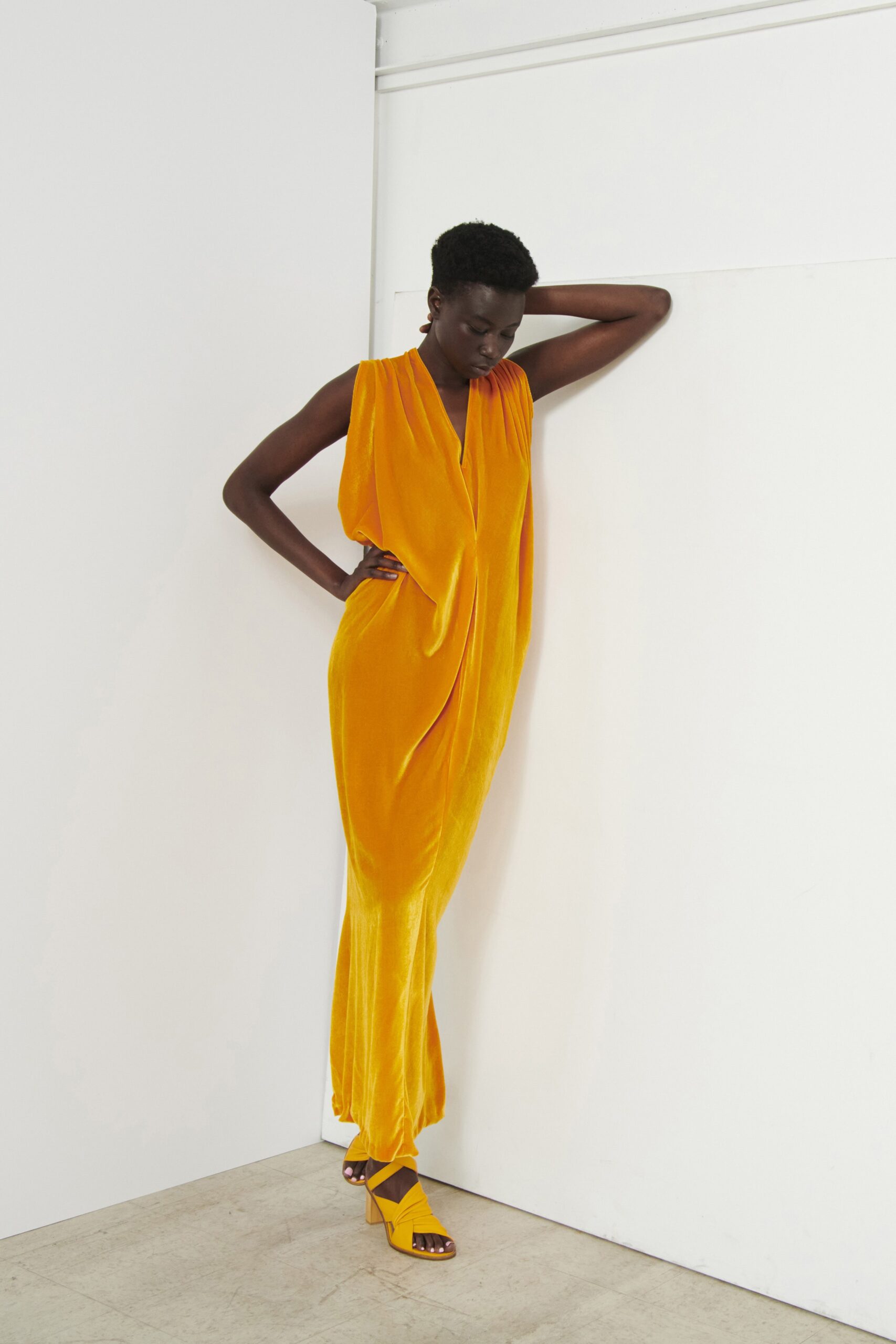 A relaxed yellow velvet sleeveless dress featuring a V-neckline and draped design.