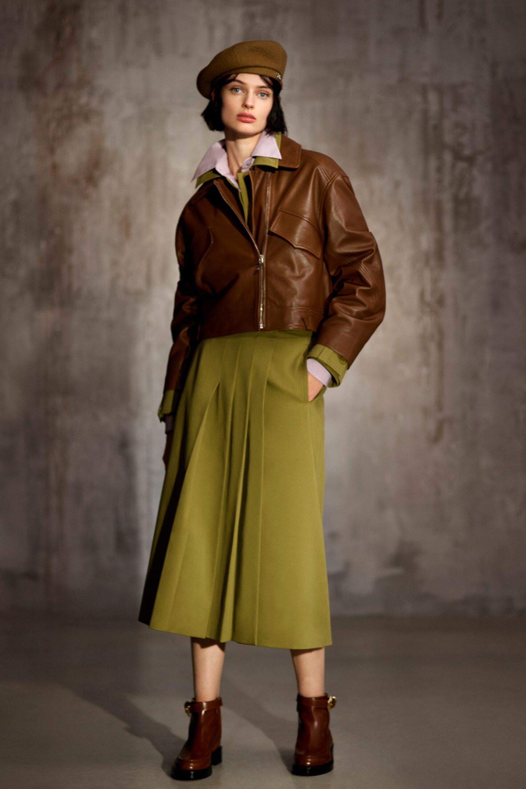 brown leather jacket with green pleated skirt