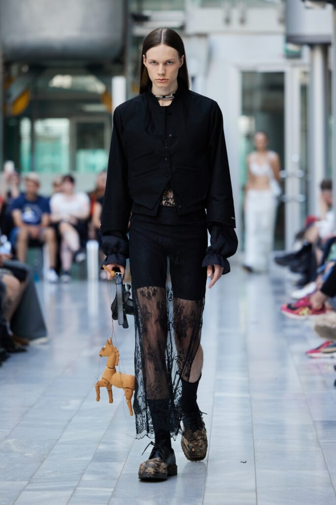 A fitted black lace top paired with a sheer black lace skirt, creating a dramatic runway look.