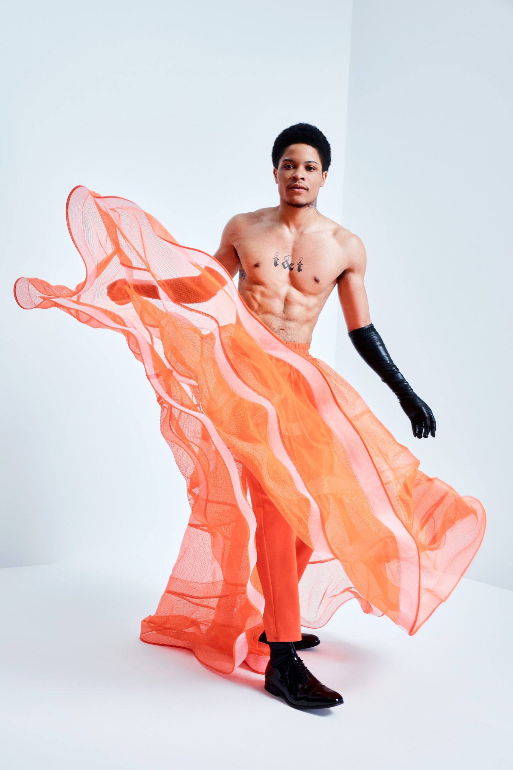 This striking dress features a high-neck design and a sleeveless silhouette, crafted from sheer fabric that creates a dynamic interplay of layers. The flowing movement of the garment adds an ethereal quality, while the fitted pants provide a contemporary contrast, enhancing the overall visual impact.