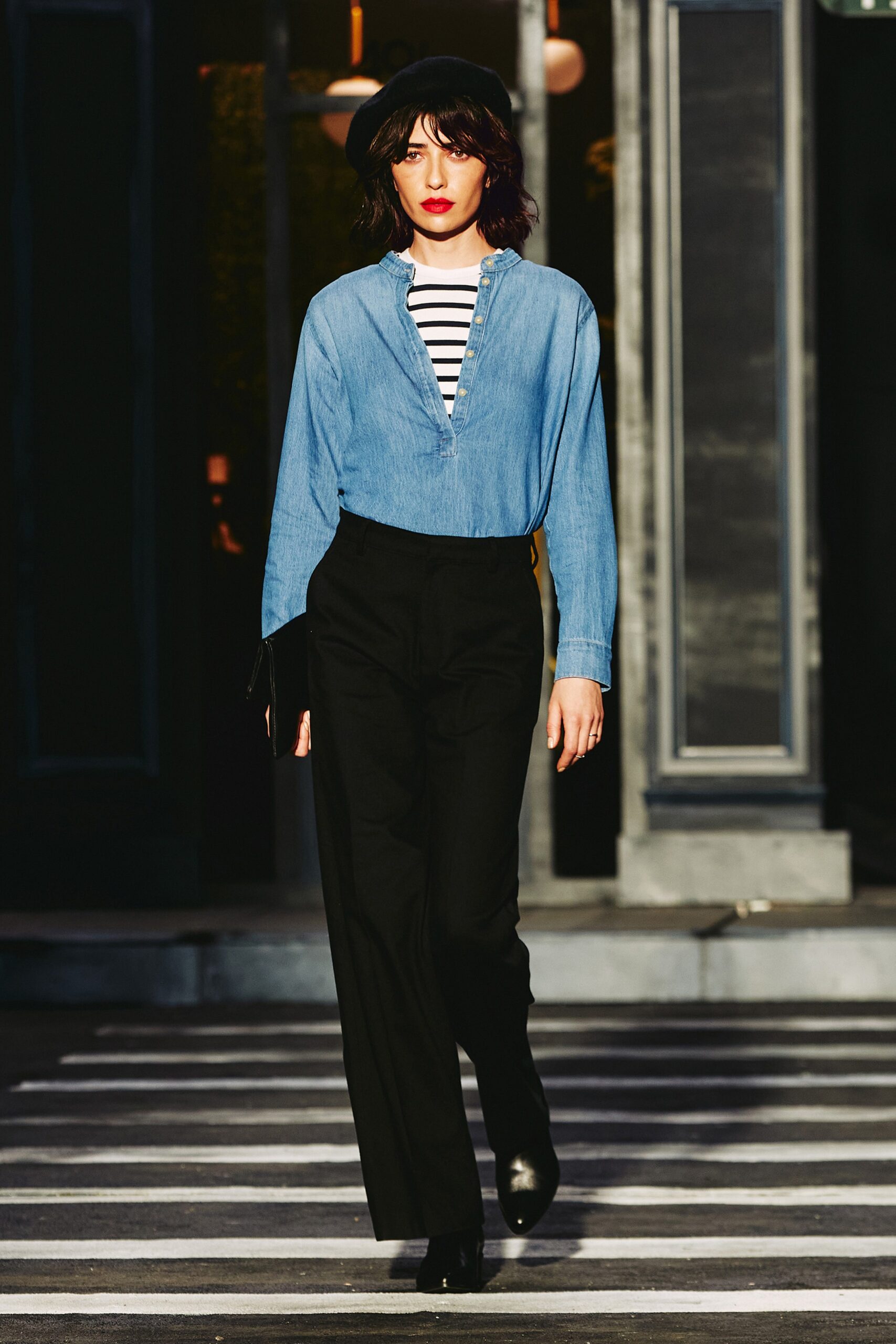 A fitted blue denim long-sleeve shirt with a collar paired with straight-leg black pants.