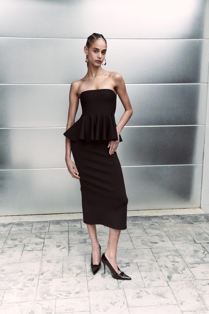 A fitted black strapless dress with a peplum detail, perfect for formal occasions.