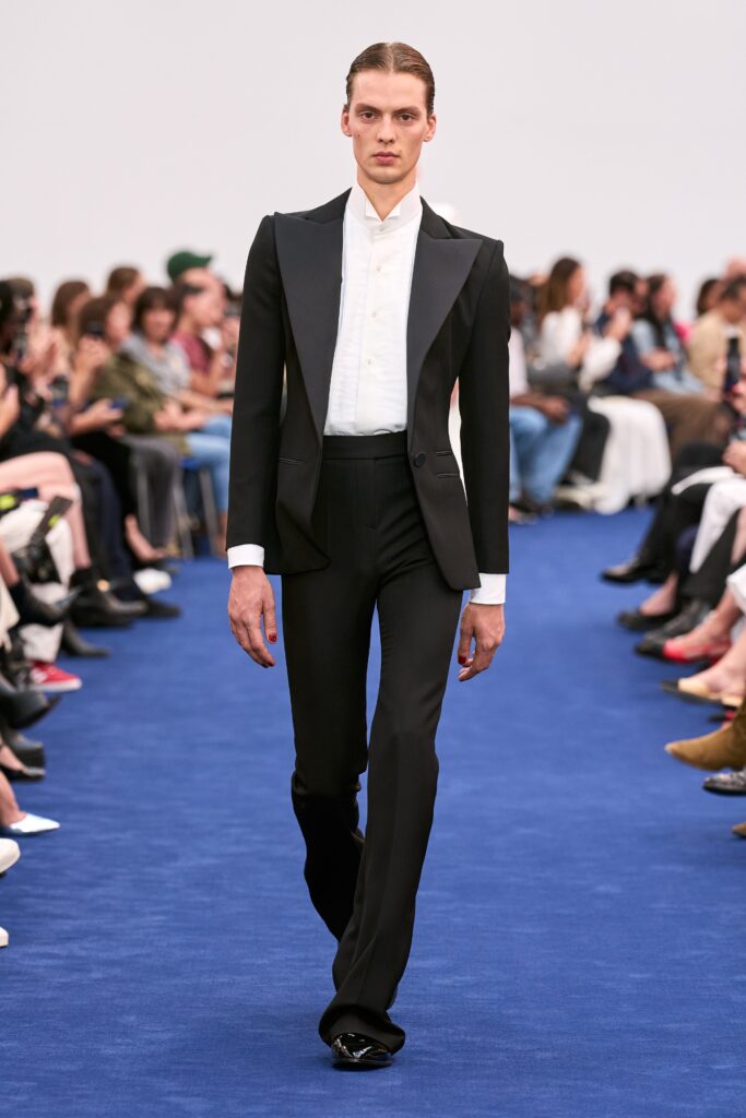 A tailored black suit with a long-sleeve collared shirt and straight-leg trousers.