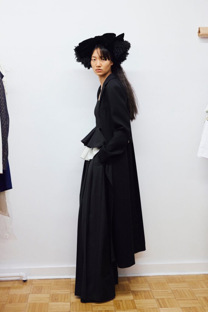 A fitted black dress with a V-neckline and asymmetric design details.