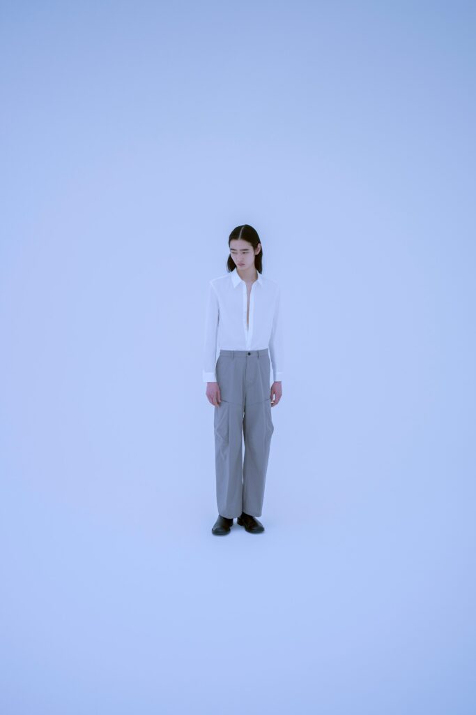 A relaxed white collared shirt paired with straight-leg gray pants for a modern look.