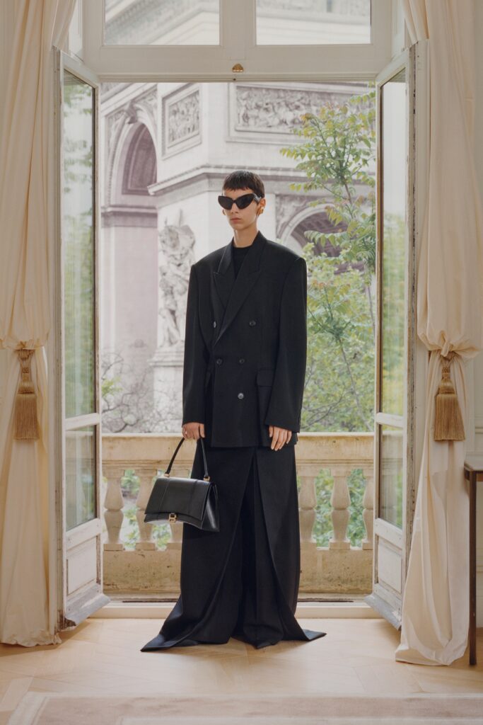 A fitted black wool long-sleeve dress with a V-neckline and asymmetric design.