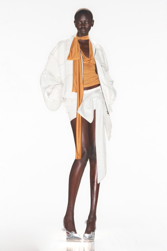 An oversized white jacket paired with a gold top featuring an asymmetric design.