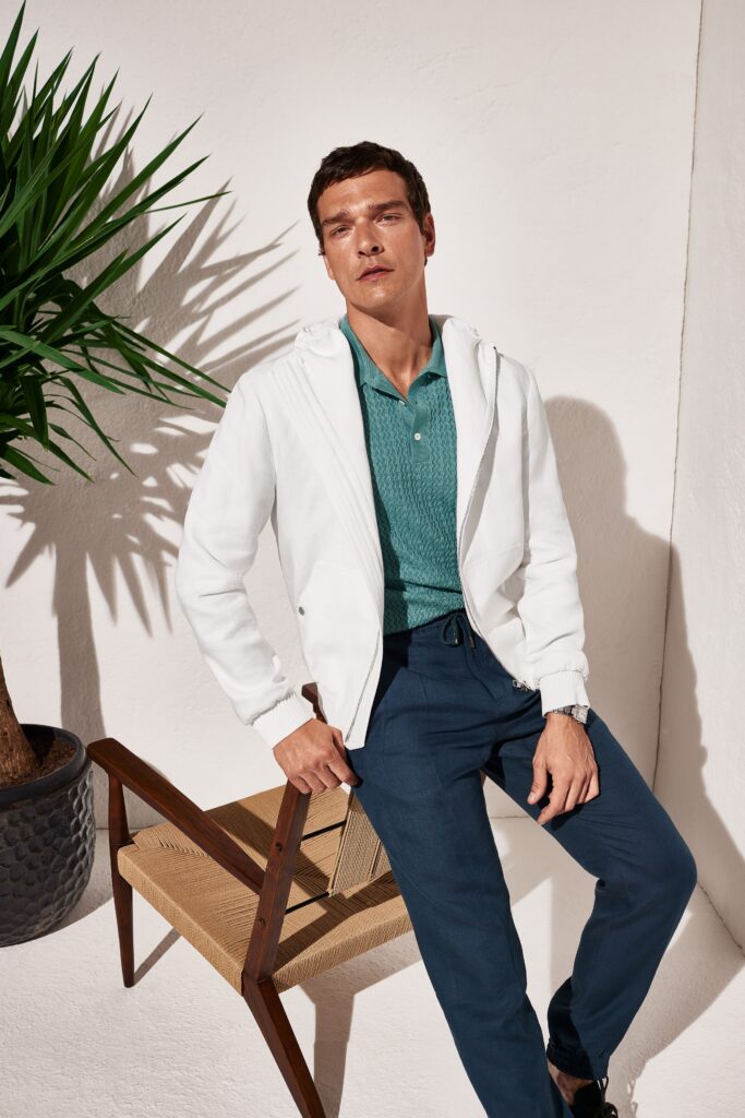 A relaxed white cotton jacket with a collared neckline paired with blue pants.