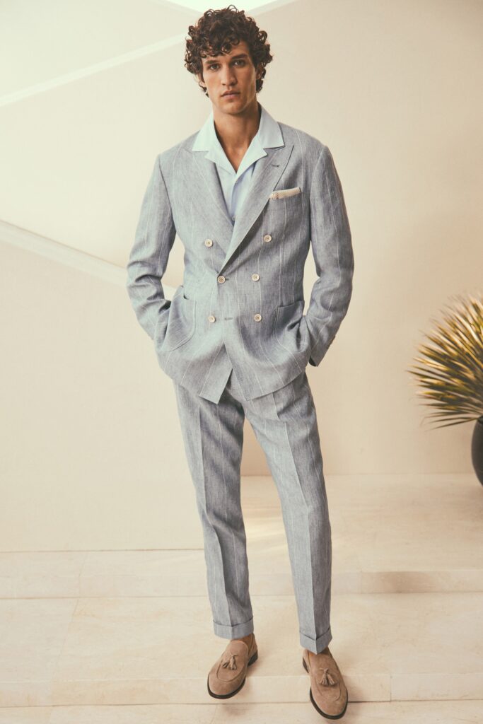 A tailored blue cotton suit with long sleeves and a collared shirt, featuring buttoned details.