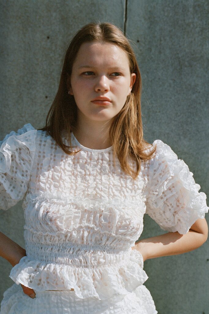 A fitted white cotton top with short sleeves and ruffles, paired with a tiered skirt.