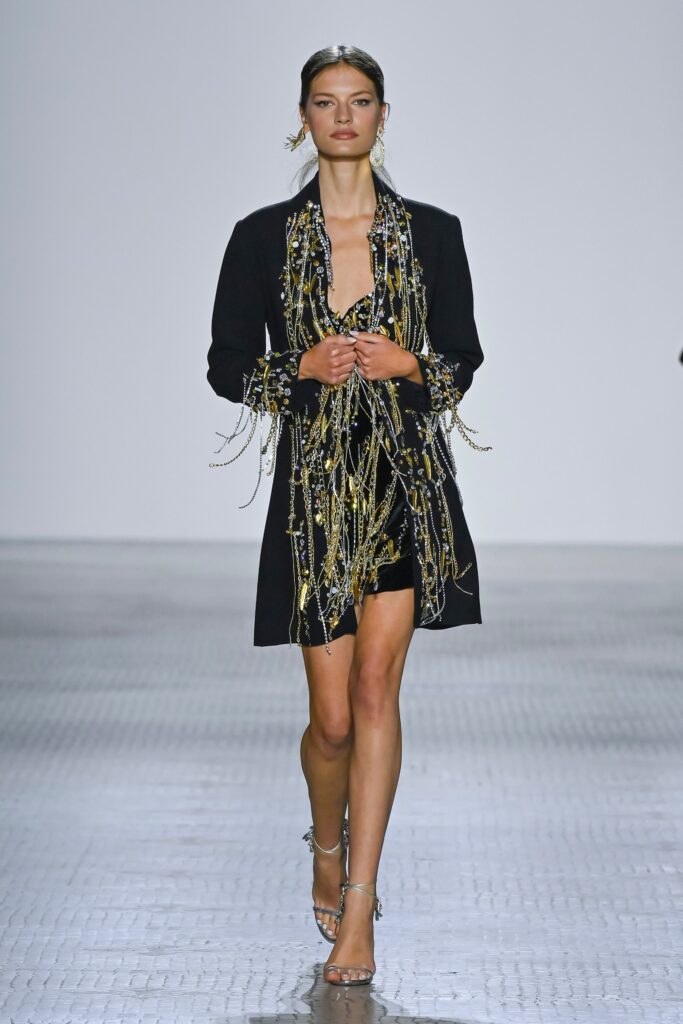 A fitted black silk dress with a long-sleeve jacket featuring embroidered details.