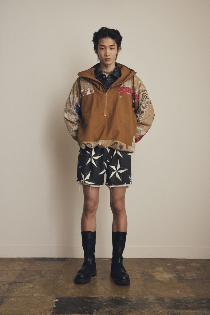 A relaxed brown printed jacket with a collared neckline paired with black star-patterned shorts.