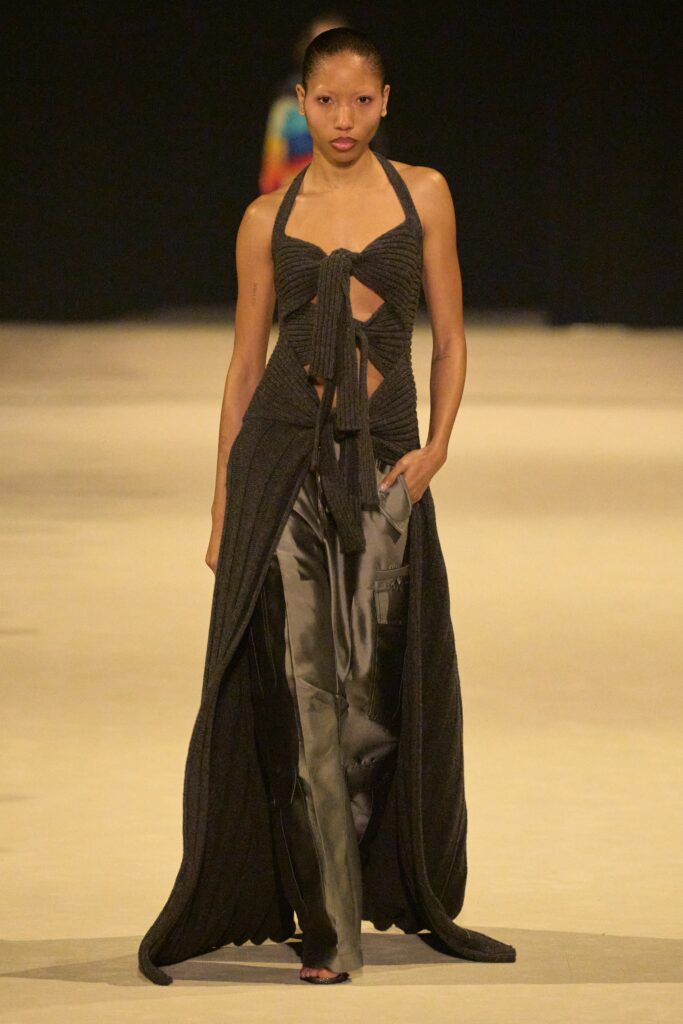 A fitted black halter dress with an asymmetric design paired with fitted pants.
