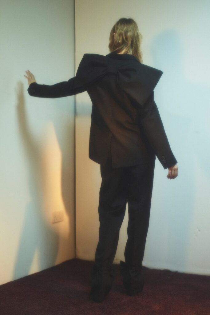 A tailored black blazer with an asymmetric design paired with matching pants.