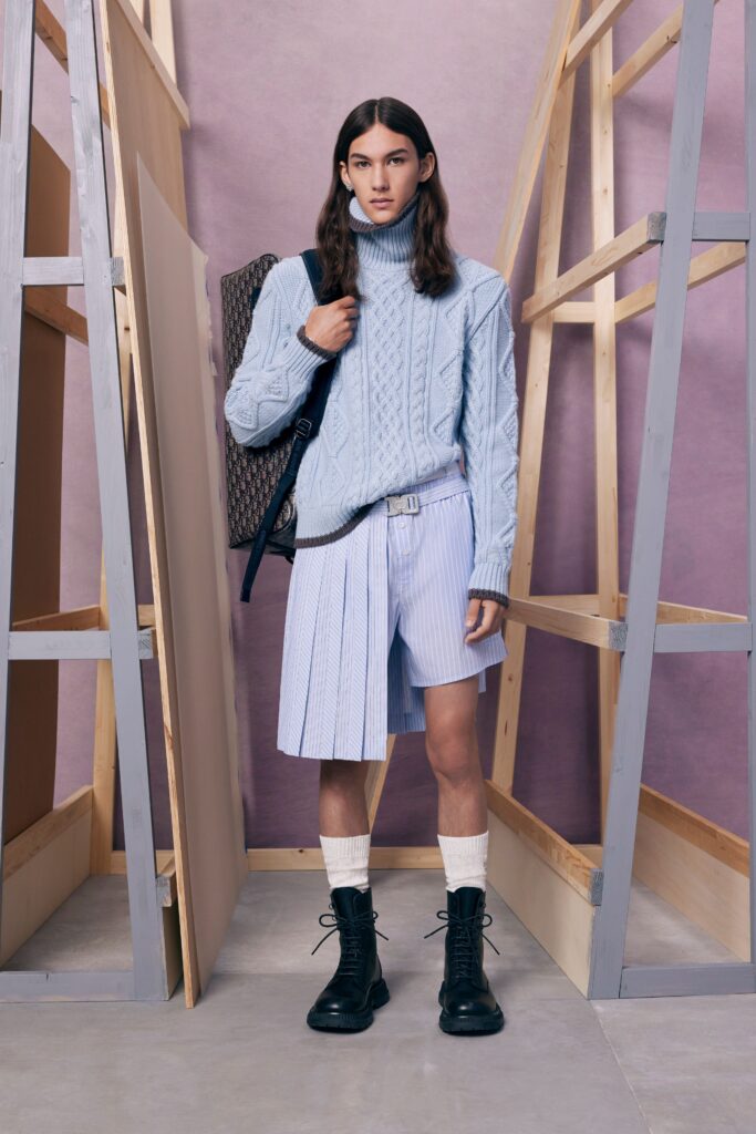 An oversized blue cotton sweater paired with pleated white shorts and combat boots.