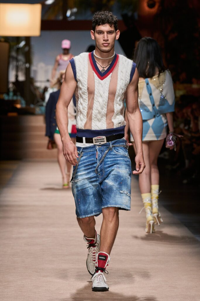 A fitted white sleeveless sweater with a V-neck and blue denim shorts.