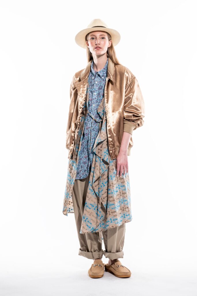 A relaxed gold jacket layered over a printed blue shirt with long sleeves and a collared neckline.