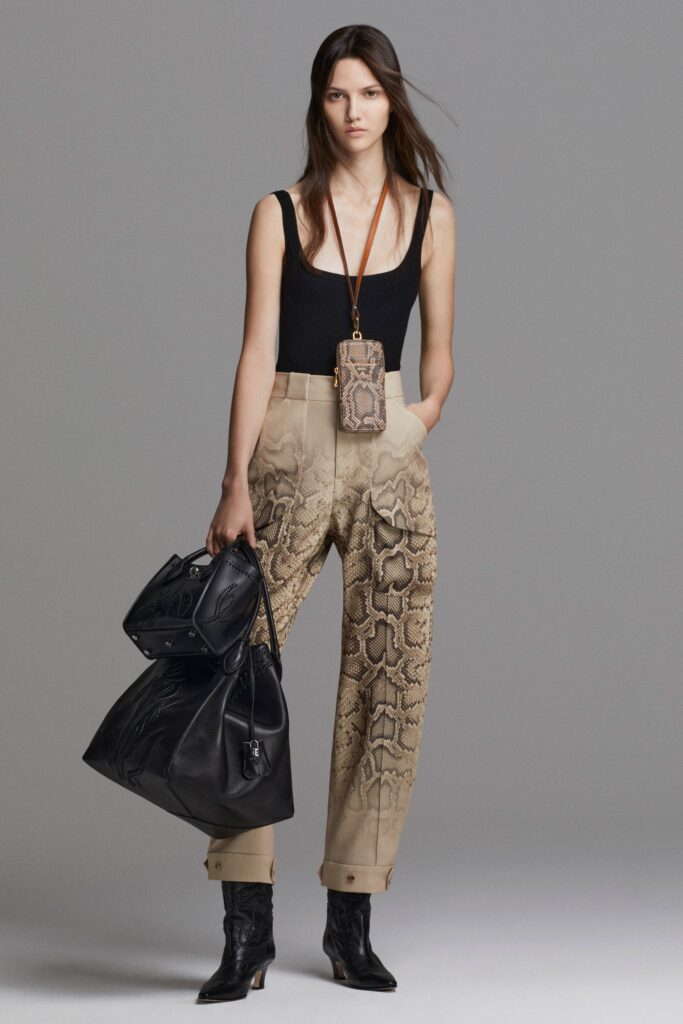 A fitted black sleeveless top paired with high-waisted beige pants featuring a printed design.