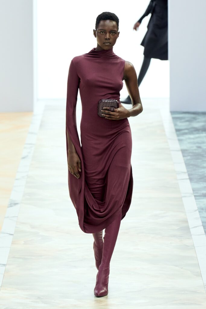 A fitted burgundy long-sleeve dress with a high-neck and asymmetric design detail.