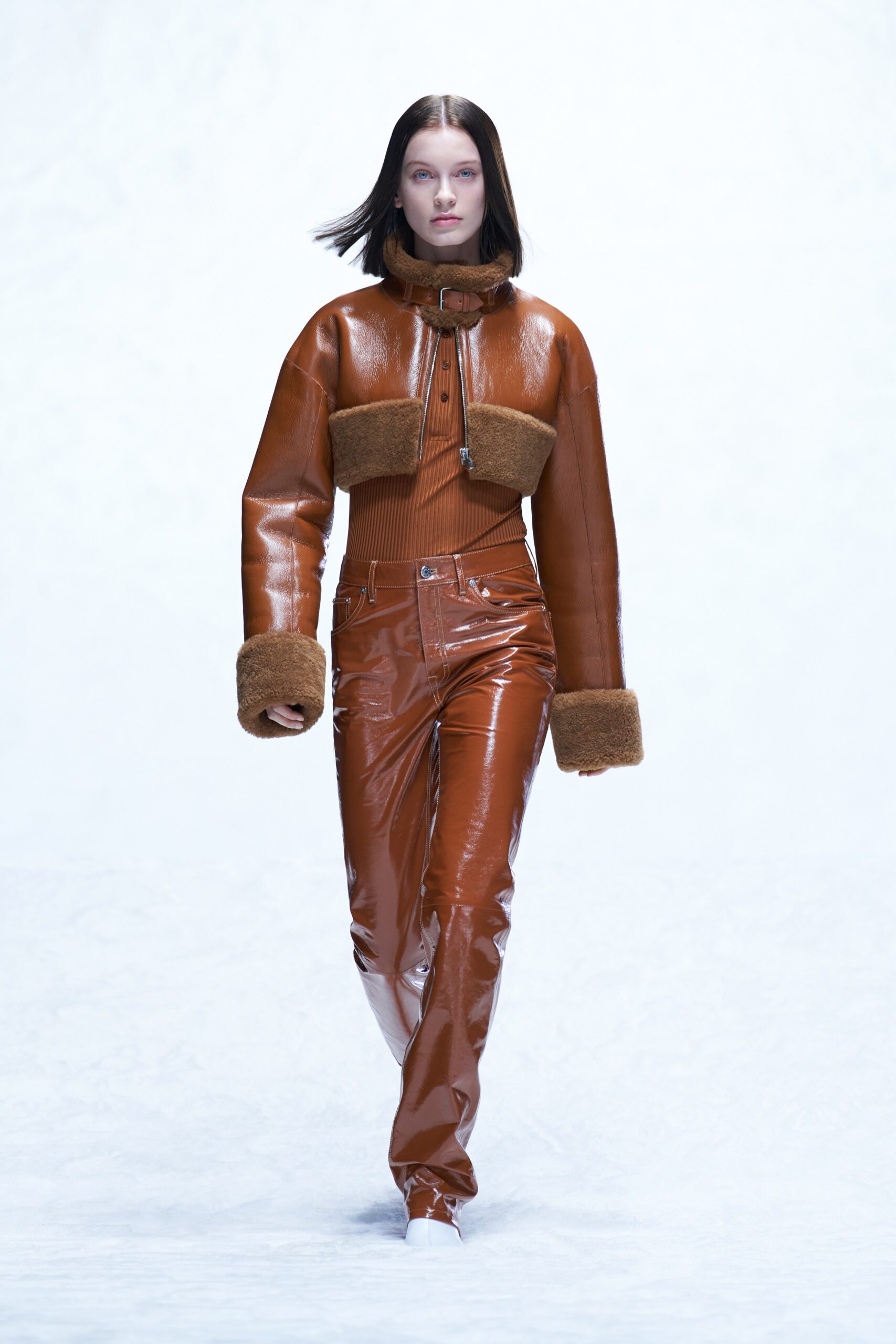 A fitted brown leather jacket with a collared design paired with straight-leg leather pants.