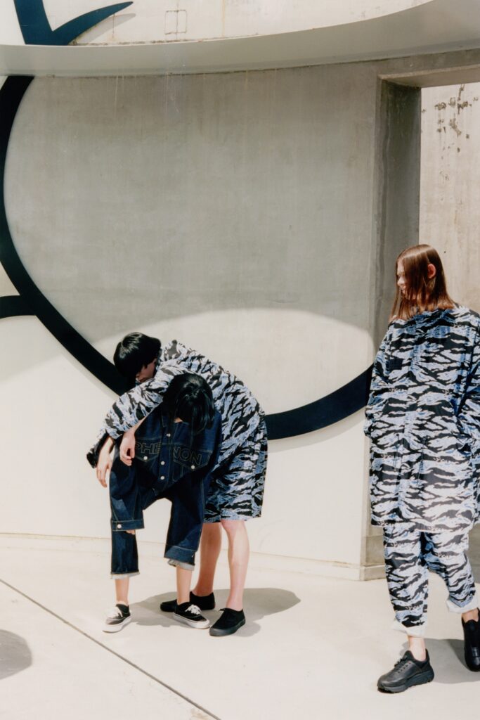 A relaxed blue denim jumpsuit with long sleeves and a collared neckline featuring a printed design.