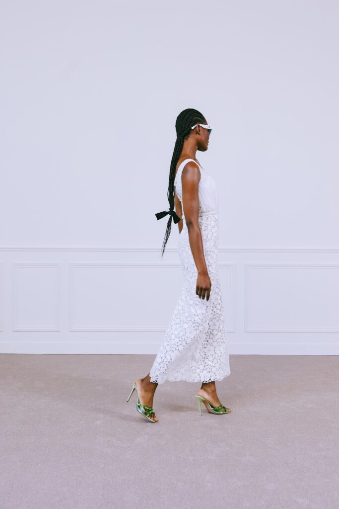 A fitted white lace dress with a sleeveless and backless design, featuring a maxi length.