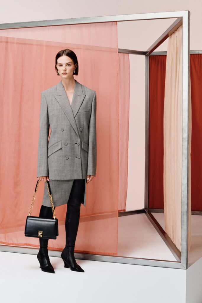 A fitted gray wool blazer paired with a black leather skirt featuring an asymmetric design.