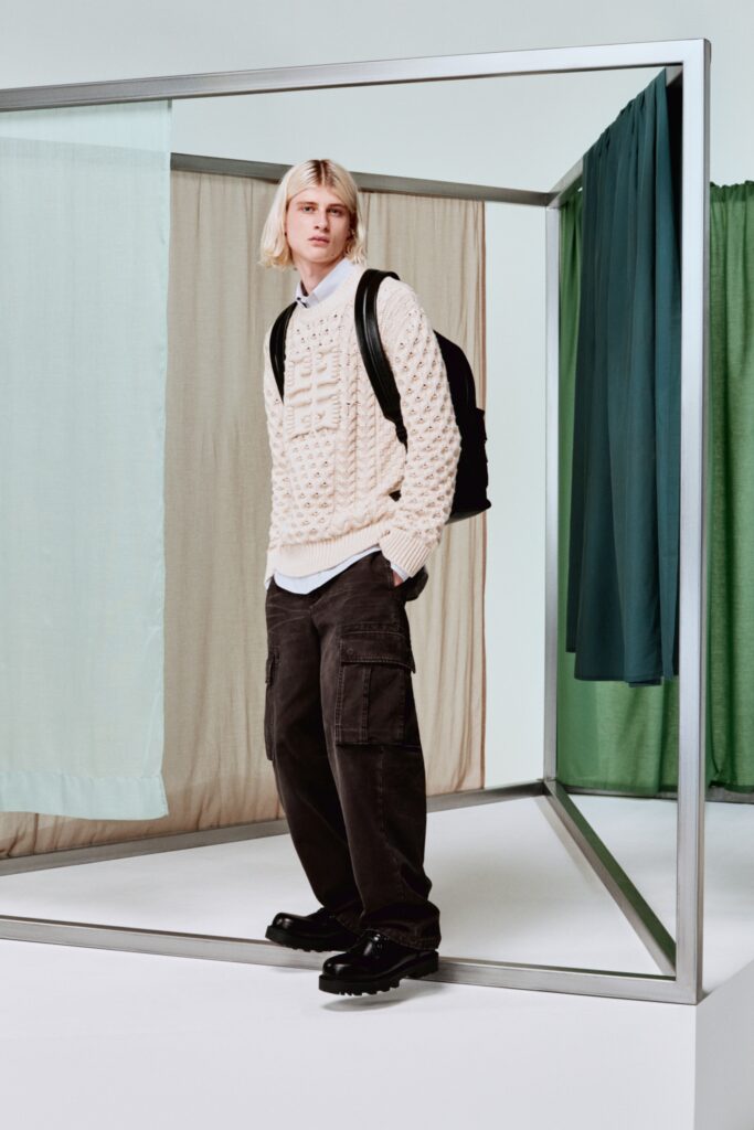 A relaxed beige textured sweater paired with black pants for a casual look.