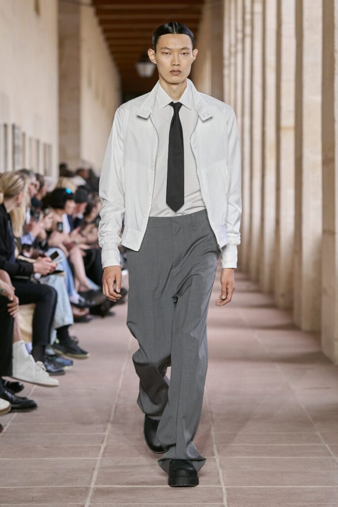 A relaxed white jacket paired with gray straight-leg pants and a collared shirt.