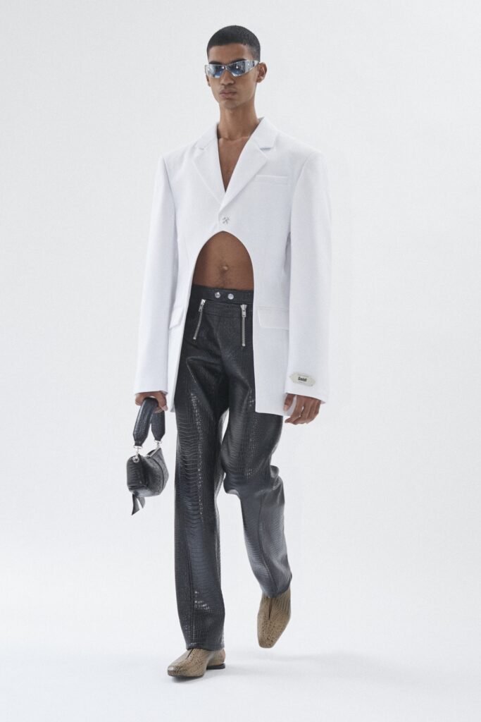 An oversized white collared jacket paired with black zippered pants for a striking look.