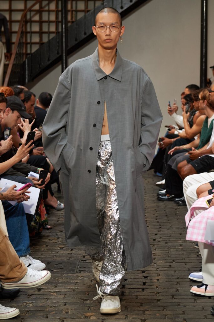 An oversized gray coat paired with metallic silver straight-leg pants.
