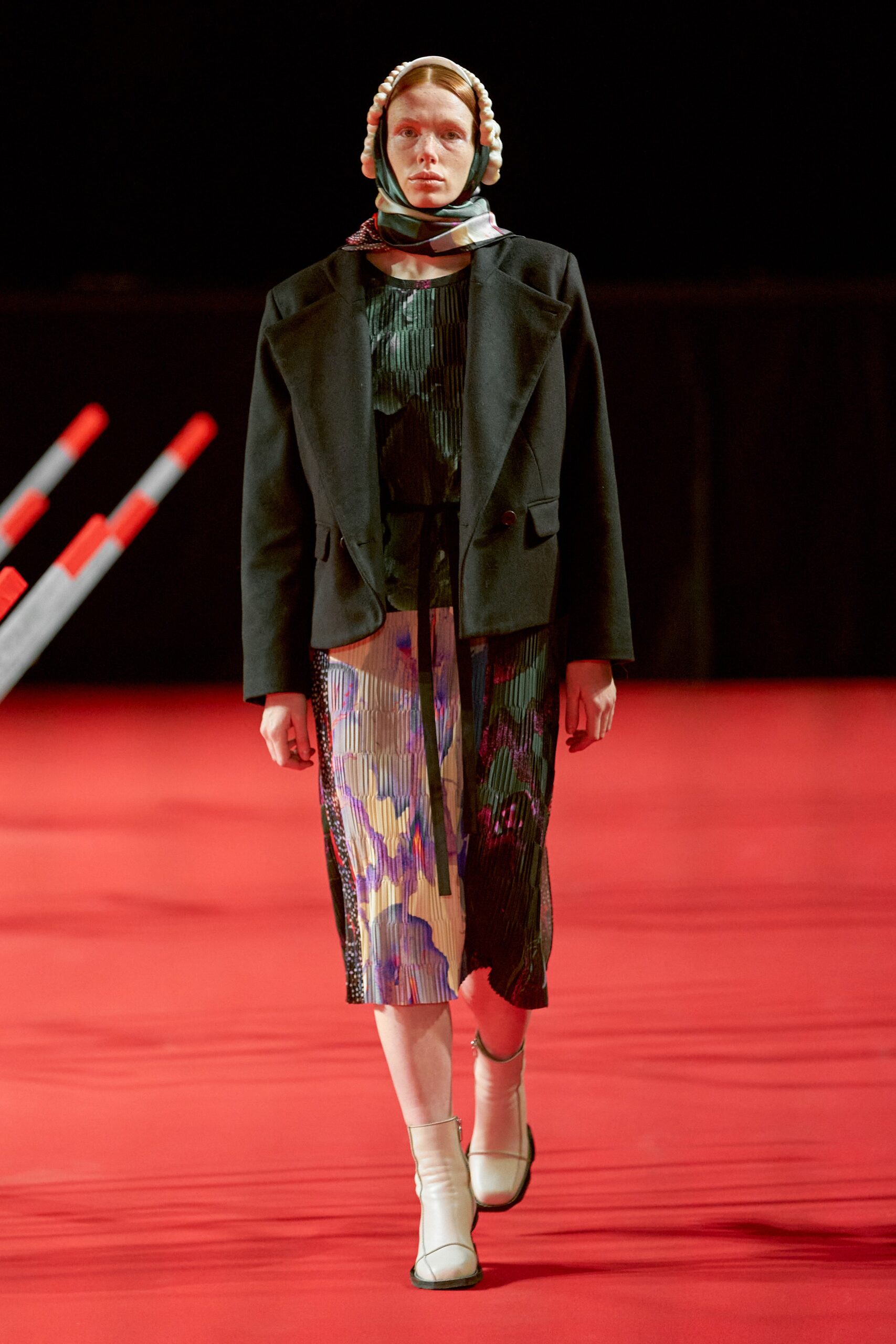 A fitted black and multicolor layered dress paired with a long-sleeve collared jacket.