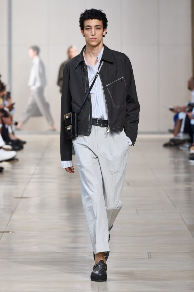 A relaxed black jacket with a collared neckline paired with white straight-leg pants.