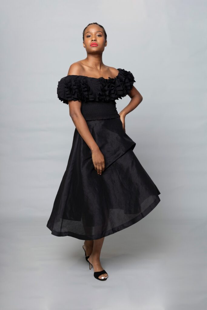 A fitted black dress with ruffled off-shoulder detail and A-line silhouette.