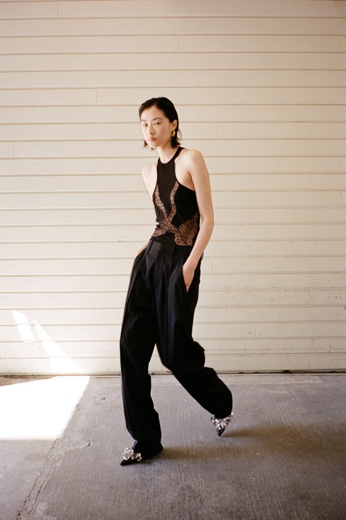 A relaxed black sleeveless top with an asymmetric design paired with loose-fitting pants.