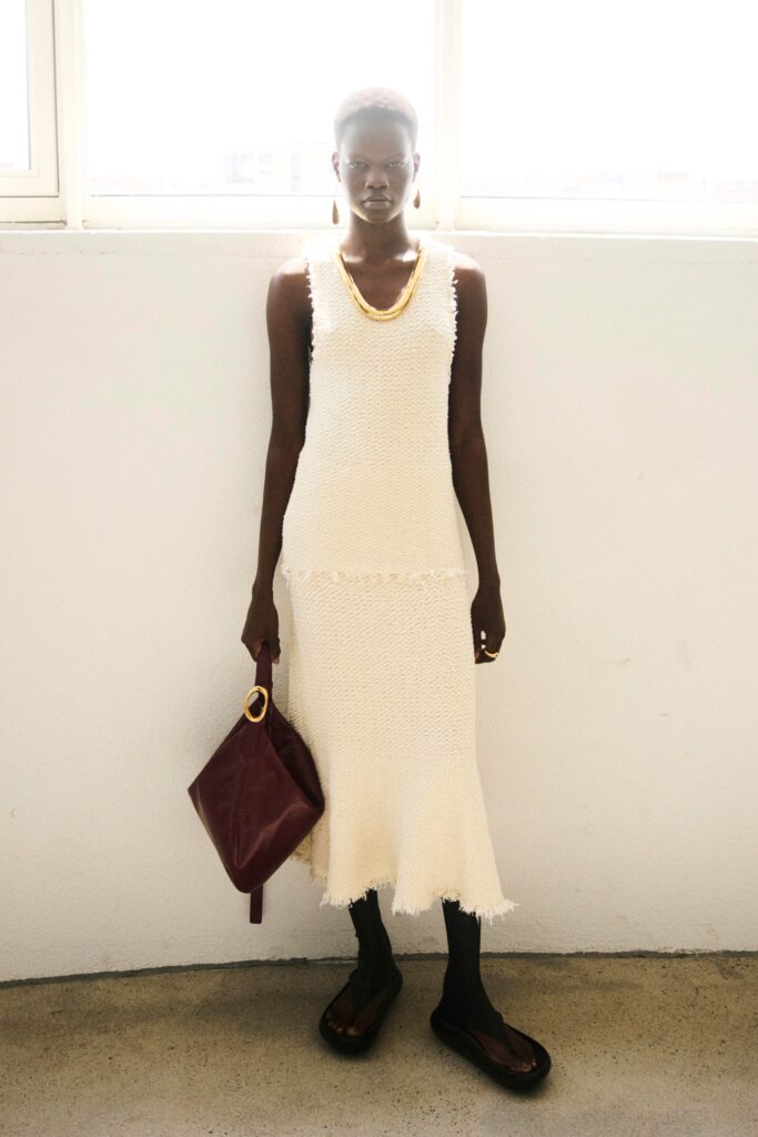 A fitted white cotton sleeveless dress with a high-neck and tiered design.