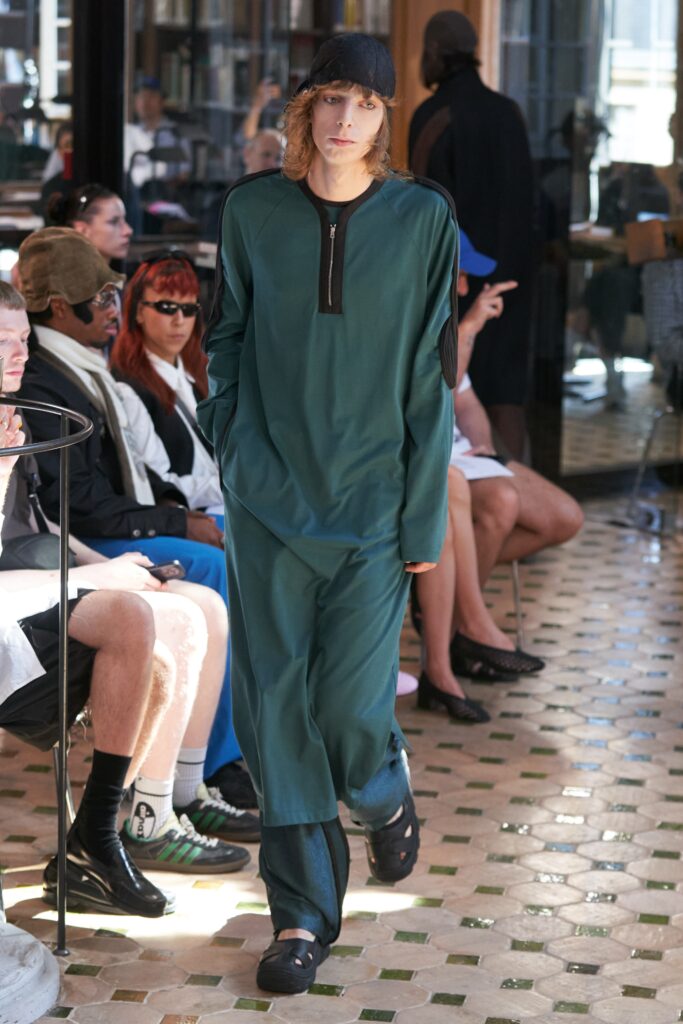 A relaxed green jumpsuit with long sleeves and a zippered collar detail.