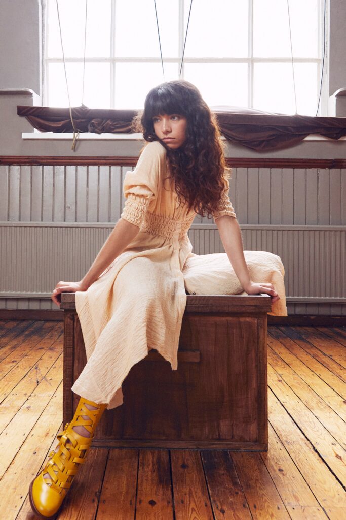 A relaxed beige cotton dress with short sleeves and a V-neckline featuring a tiered design.
