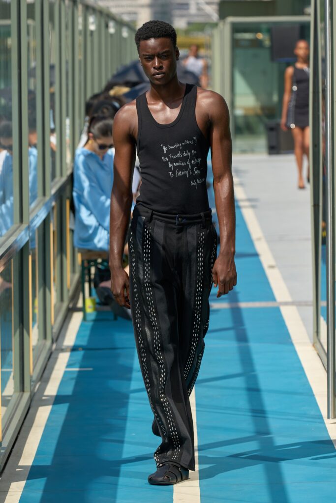 A fitted black sleeveless tank-top paired with high-waisted straight-leg pants.