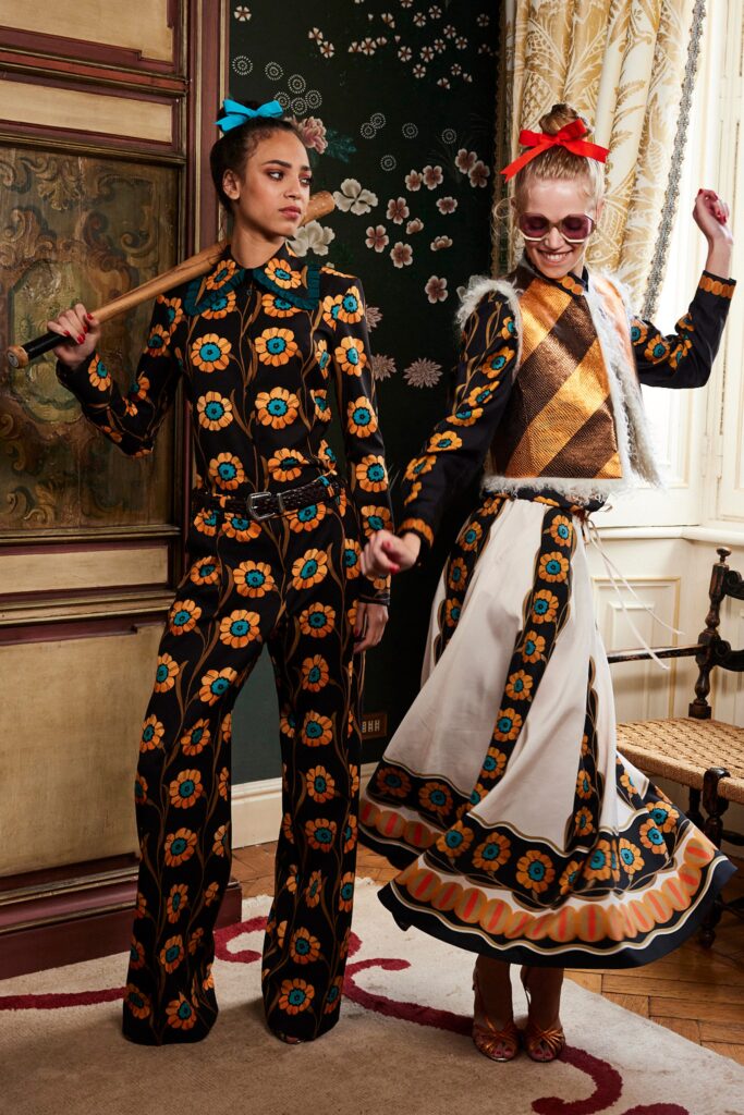 A fitted black and orange printed dress with long sleeves and a flared silhouette.